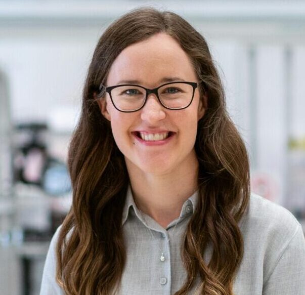 Smiling woman engineer standing confidently in a modern industrial workshop setting.
